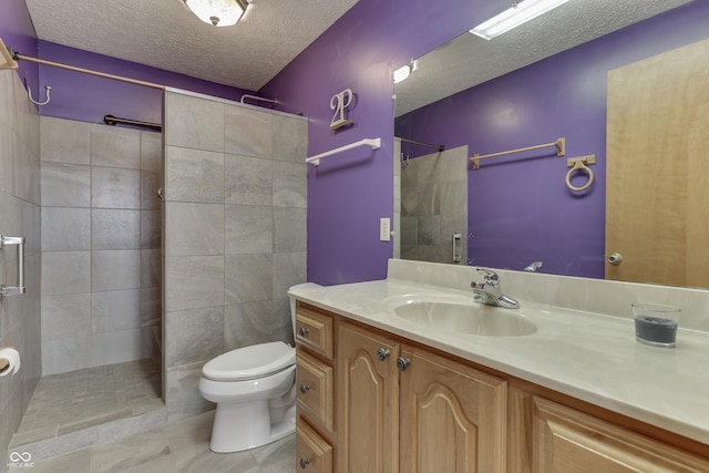 full bath with tile patterned floors, toilet, a textured ceiling, tiled shower, and vanity