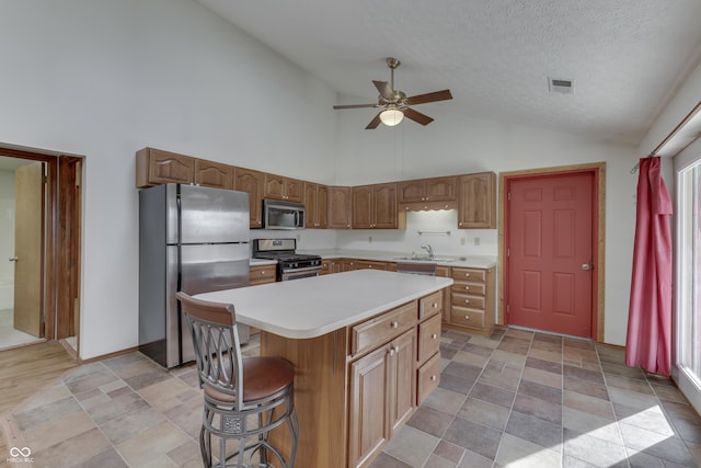 kitchen featuring visible vents, a kitchen island, ceiling fan, light countertops, and stainless steel appliances