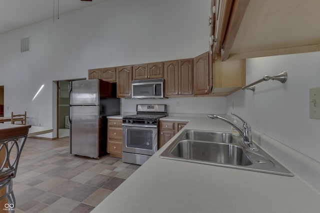 kitchen with visible vents, light countertops, appliances with stainless steel finishes, a high ceiling, and a sink