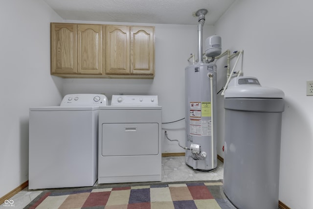 clothes washing area with washer and clothes dryer, gas water heater, cabinet space, baseboards, and light floors