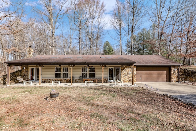 view of front of home with driveway, an attached garage, a chimney, ceiling fan, and stone siding