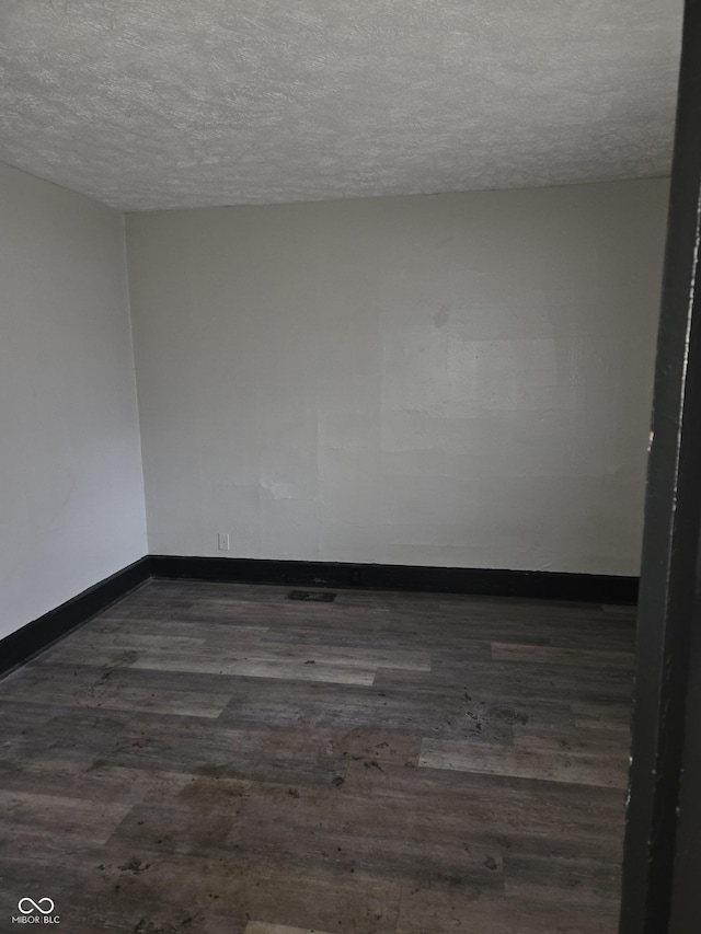 empty room featuring dark wood-style floors, baseboards, and a textured ceiling