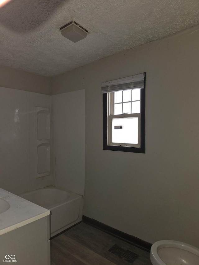 full bath with baseboards, toilet, vanity, wood finished floors, and a textured ceiling