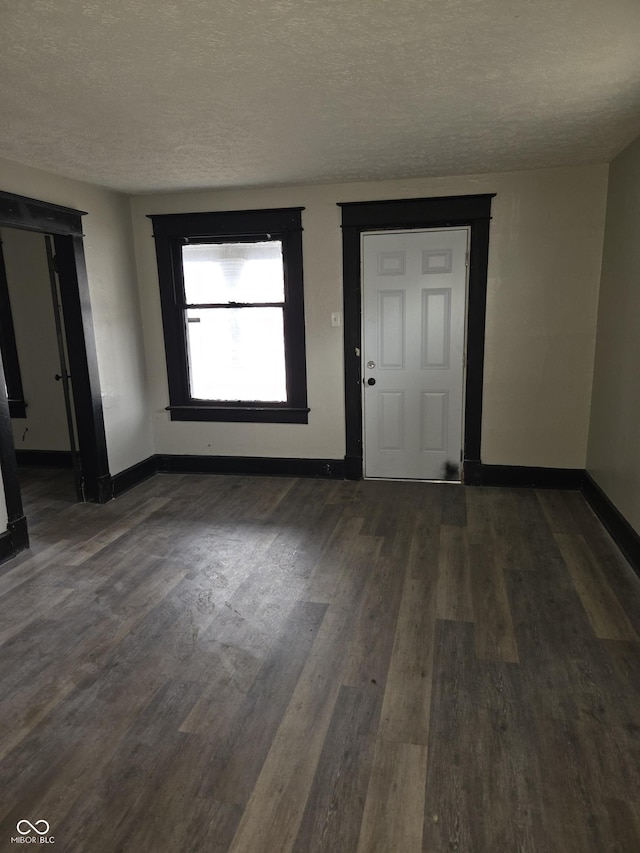 interior space with dark wood finished floors, a textured ceiling, and baseboards