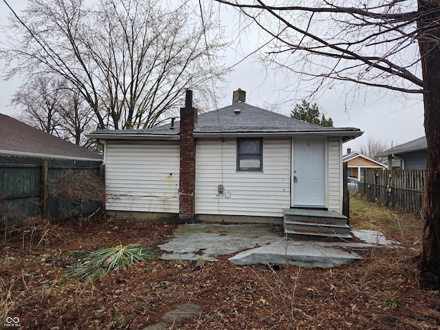 rear view of house featuring fence, a chimney, and entry steps