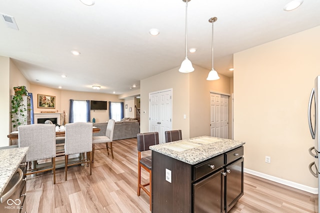 kitchen featuring light wood finished floors, visible vents, baseboards, a breakfast bar area, and appliances with stainless steel finishes