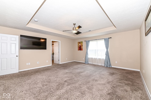 interior space featuring a tray ceiling, visible vents, baseboards, and ceiling fan