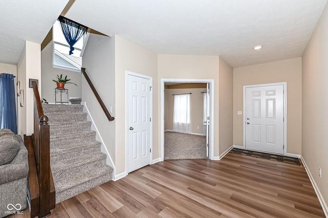 entrance foyer with stairway, wood finished floors, and baseboards