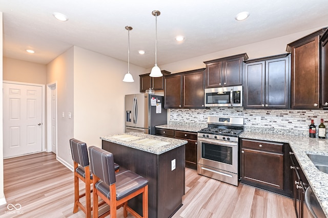 kitchen with light wood-type flooring, a center island, tasteful backsplash, and stainless steel appliances