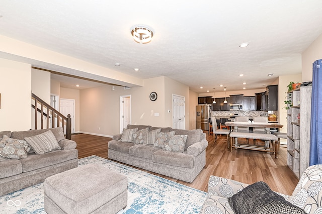 living room with recessed lighting, stairway, baseboards, and light wood-style floors