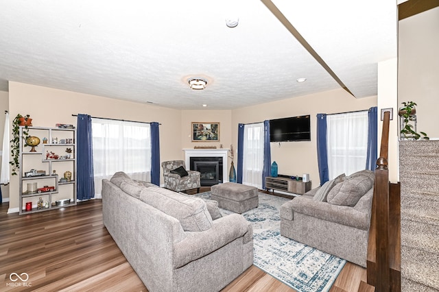 living room with a glass covered fireplace, wood finished floors, and a textured ceiling