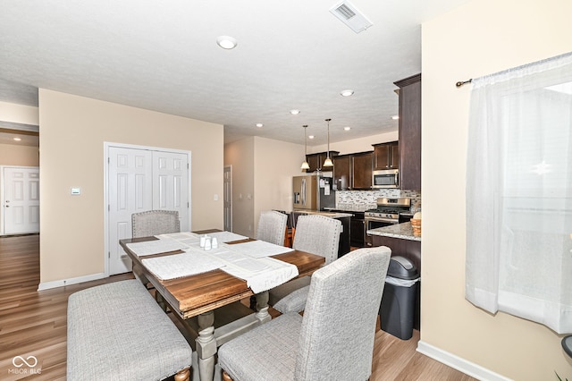 dining space with light wood-type flooring, baseboards, and visible vents