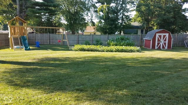 view of yard featuring a storage shed, a playground, a fenced backyard, and an outdoor structure