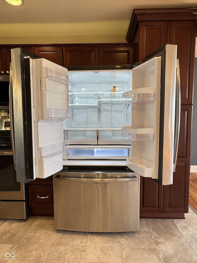 kitchen with dark brown cabinetry, light countertops, freestanding refrigerator, and stove