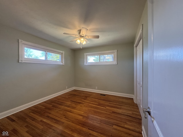 unfurnished bedroom featuring visible vents, dark wood-type flooring, ceiling fan, baseboards, and a closet