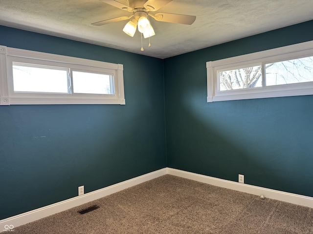 carpeted spare room featuring a healthy amount of sunlight and baseboards