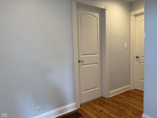 hall with visible vents, baseboards, and wood finished floors