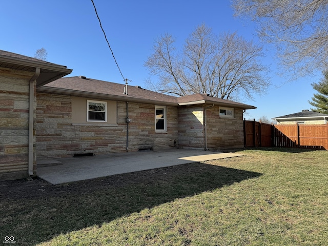 rear view of property with a patio, fence, a lawn, and stone siding