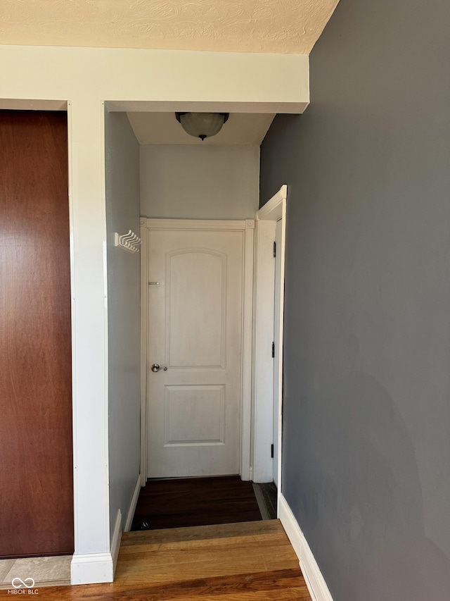 corridor with wood finished floors and baseboards