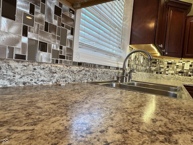 interior details with decorative backsplash, dark brown cabinets, and a sink