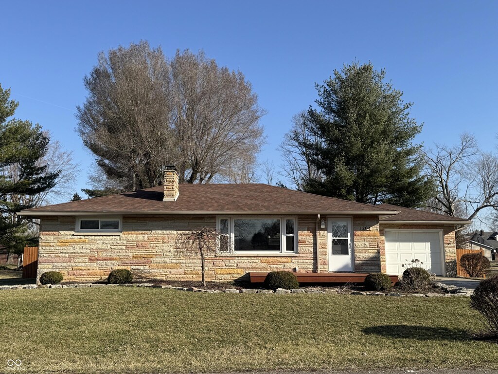 204 W Pullman St, Waldron, IN 46182 - single story home featuring a garage, stone siding, a chimney, and a front lawn