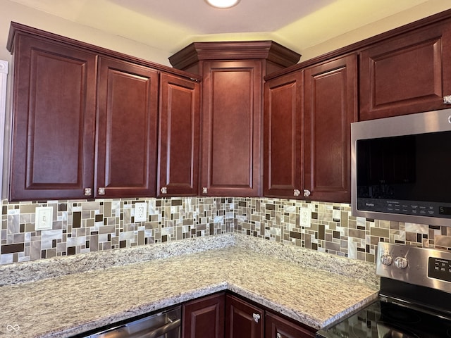 kitchen with light stone counters, dark brown cabinets, tasteful backsplash, and appliances with stainless steel finishes