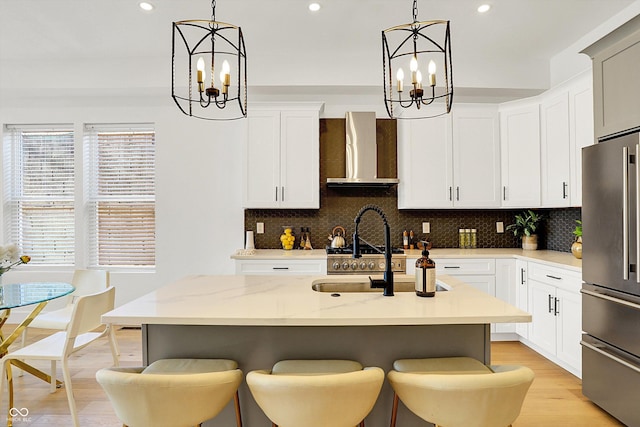 kitchen featuring a notable chandelier, high quality fridge, wall chimney exhaust hood, and decorative backsplash