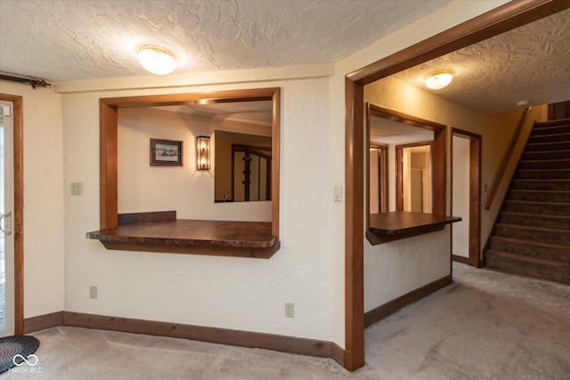 entrance foyer featuring baseboards, carpet floors, a textured ceiling, and stairs