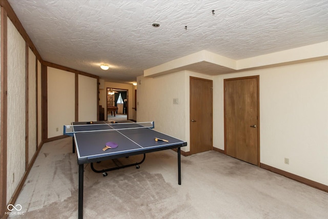 game room with a textured ceiling, baseboards, and light carpet