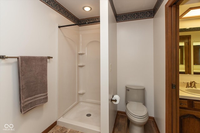 bathroom with vanity, toilet, baseboards, and a stall shower