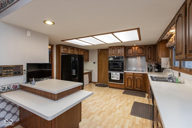 kitchen with a sink, black appliances, a peninsula, and light countertops