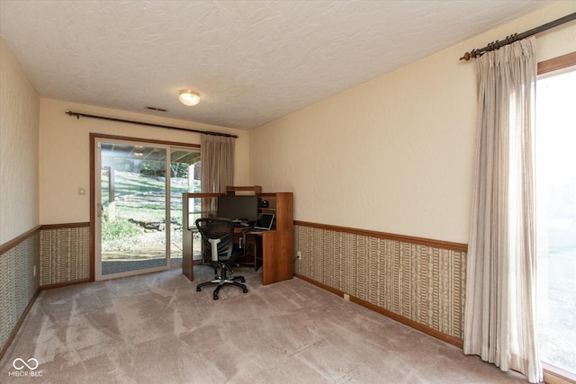 home office featuring wainscoting, a textured ceiling, wallpapered walls, and carpet