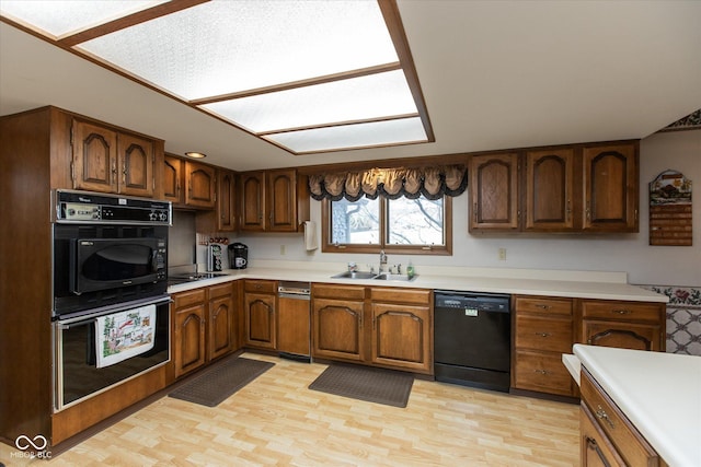 kitchen featuring black appliances, light countertops, light wood-type flooring, and a sink