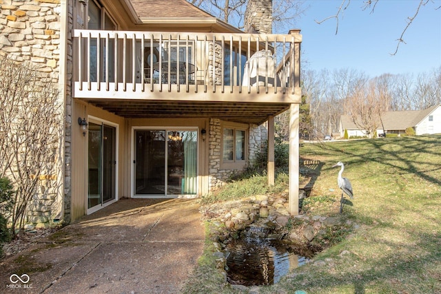 back of house featuring a lawn, stone siding, and a chimney