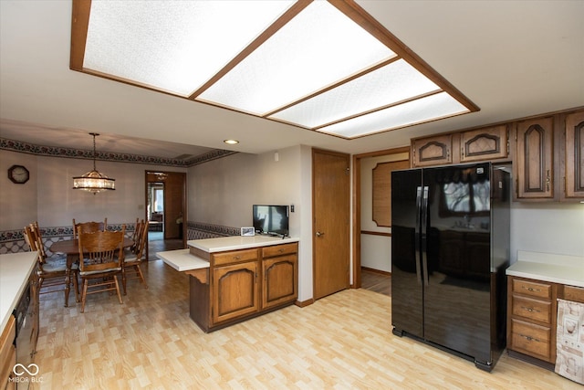 kitchen with light wood-type flooring, brown cabinets, light countertops, and freestanding refrigerator