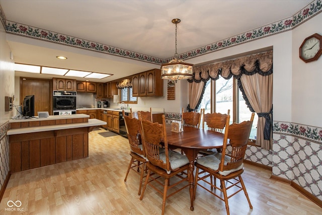 dining area with an inviting chandelier, light wood-style floors, and baseboards