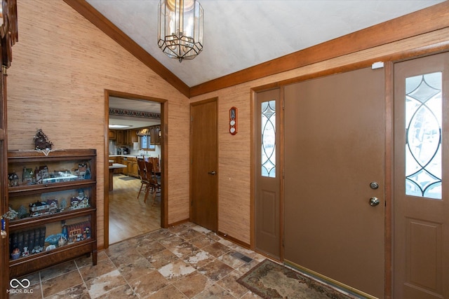 foyer entrance with an inviting chandelier, vaulted ceiling, and stone finish flooring