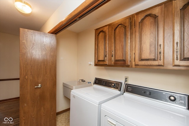 washroom featuring a sink, baseboards, cabinet space, and washing machine and clothes dryer