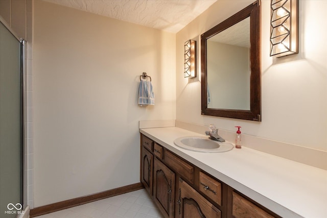 bathroom with baseboards, a textured ceiling, and vanity