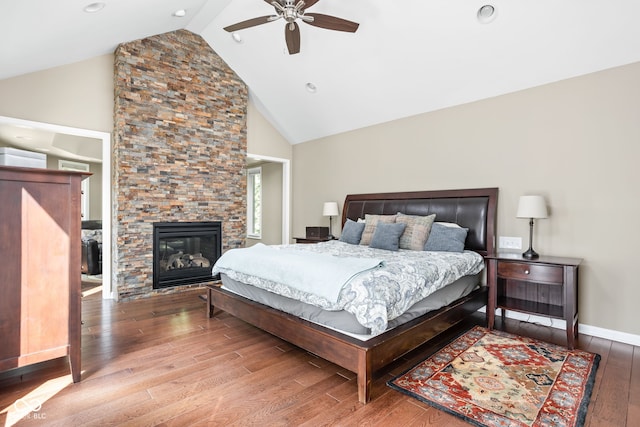 bedroom with ceiling fan, baseboards, a fireplace, hardwood / wood-style flooring, and high vaulted ceiling