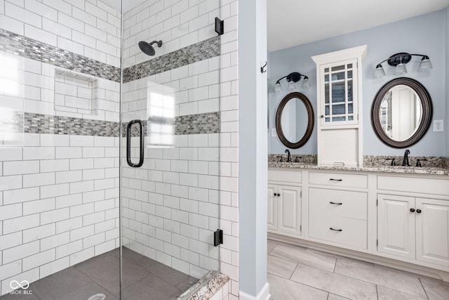 bathroom with a sink, double vanity, a shower stall, and tile patterned floors