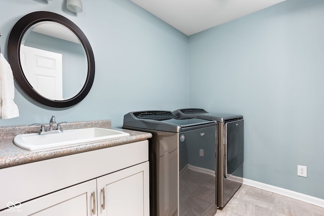 laundry room featuring baseboards, cabinet space, independent washer and dryer, and a sink