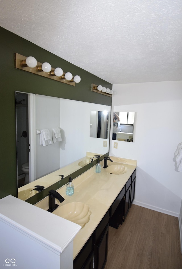 bathroom featuring a sink, a textured ceiling, wood finished floors, and toilet