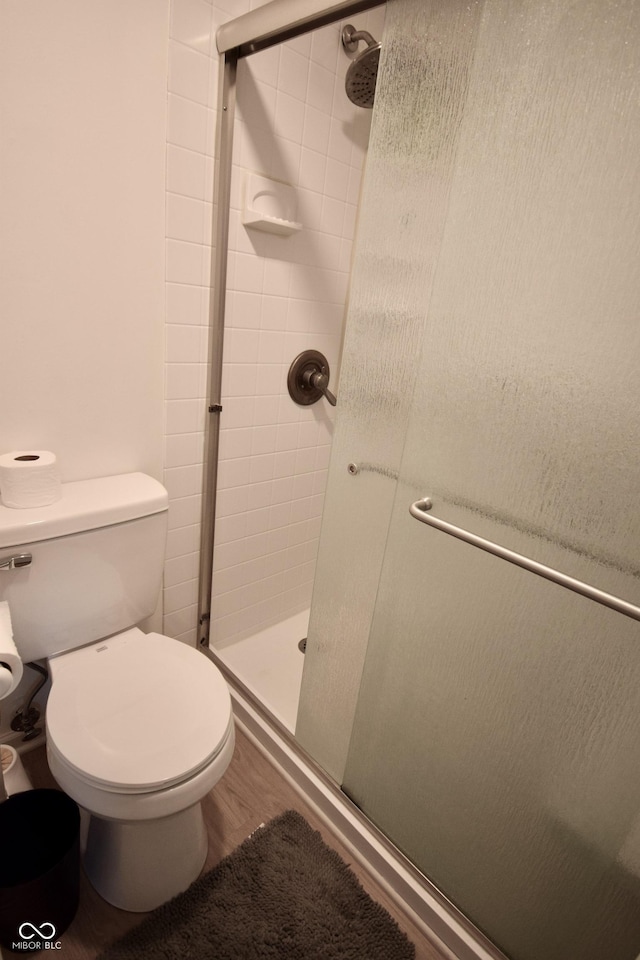 full bathroom featuring a shower stall, toilet, and wood finished floors