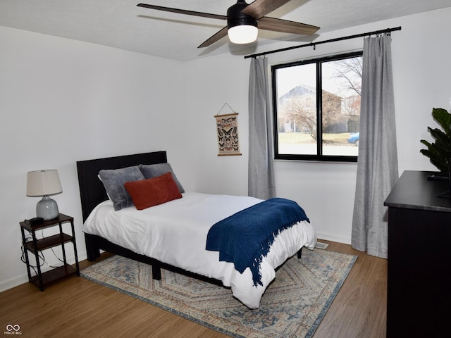 bedroom featuring baseboards, ceiling fan, and wood finished floors