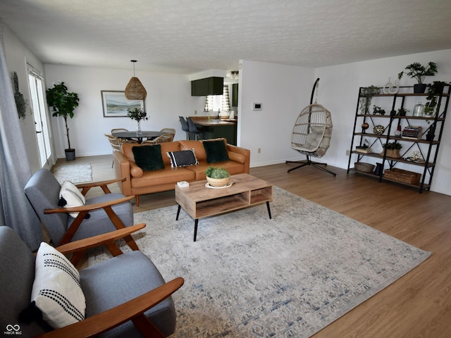 living room with light wood finished floors, a textured ceiling, and baseboards