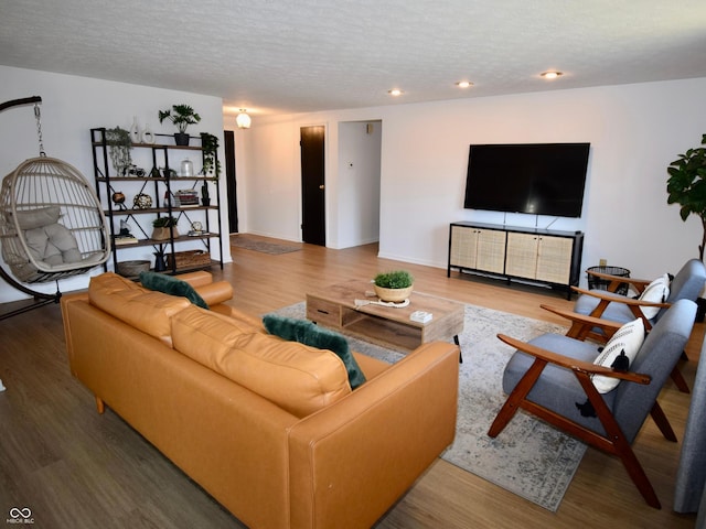 living area featuring a textured ceiling, baseboards, and wood finished floors