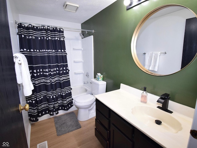 bathroom featuring visible vents, toilet, vanity, wood finished floors, and a textured ceiling