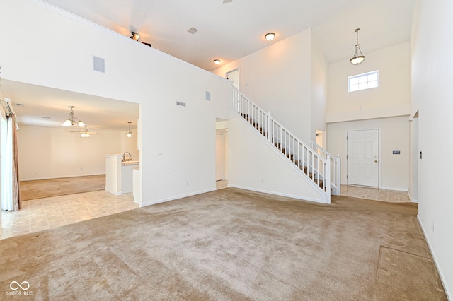 unfurnished living room featuring stairway, a ceiling fan, carpet, and a towering ceiling