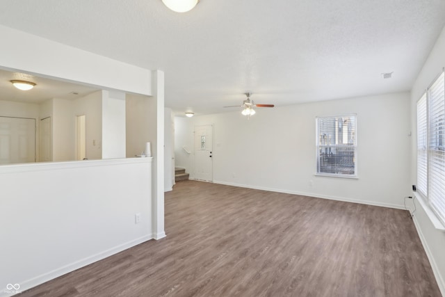 unfurnished room featuring stairs, baseboards, and wood finished floors